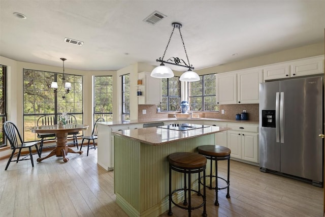 423 County Road 1010, Lampasas, TX 76550 - kitchen with stainless steel fridge, light wood-style floors, white cabinets, a kitchen island, and decorative backsplash