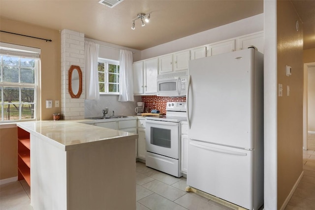 423 County Road 1010, Lampasas, TX 76550 - kitchen with white appliances, light tile patterned floors, a peninsula, a sink, and white cabinets