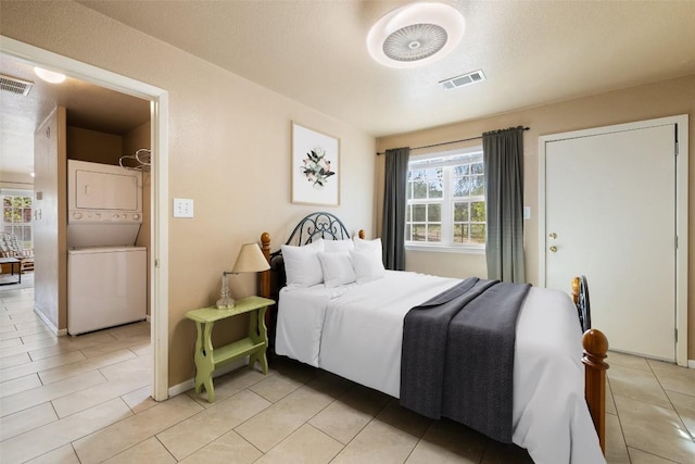 423 County Road 1010, Lampasas, TX 76550 - bedroom with stacked washing machine and dryer, multiple windows, light tile patterned flooring, and baseboards