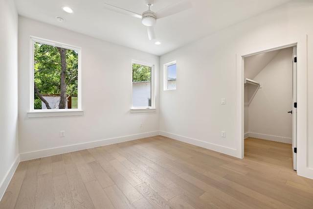 5615 Shoalwood Ave, Austin, TX 78756 - unfurnished bedroom featuring multiple windows, light wood-style flooring, a spacious closet, and recessed lighting