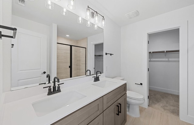 577 Tailwind Dr, Kyle, TX 78640 - bathroom featuring a spacious closet, a shower stall, toilet, double vanity, and wood finished floors