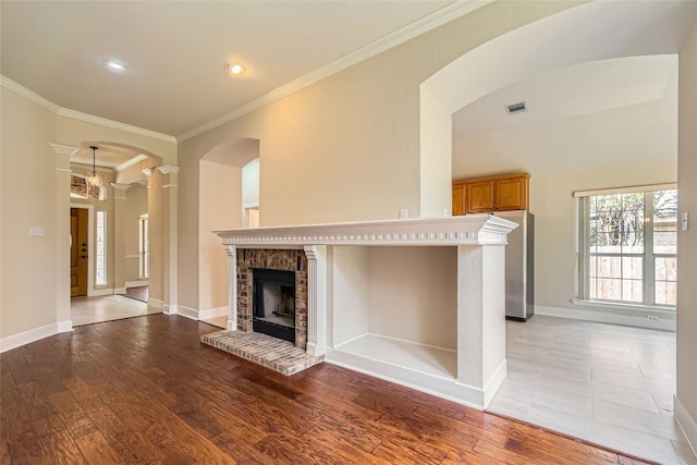6411 Abilene Trl, Austin, TX 78749 - unfurnished living room featuring crown molding, decorative columns, light wood-style flooring, arched walkways, and baseboards