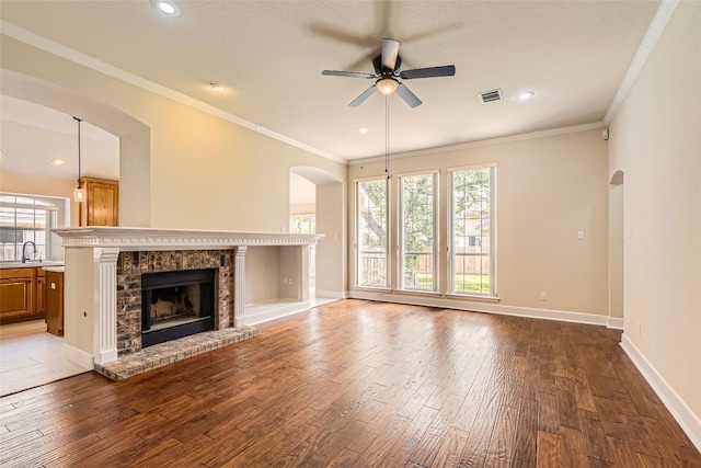 6411 Abilene Trl, Austin, TX 78749 - unfurnished living room with a ceiling fan, wood-type flooring, arched walkways, plenty of natural light, and ornamental molding