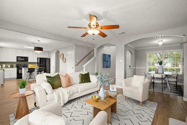 3505 Winding Shore Ln, Pflugerville, TX 78660 - living area featuring arched walkways, light wood-style flooring, stairway, a ceiling fan, and baseboards