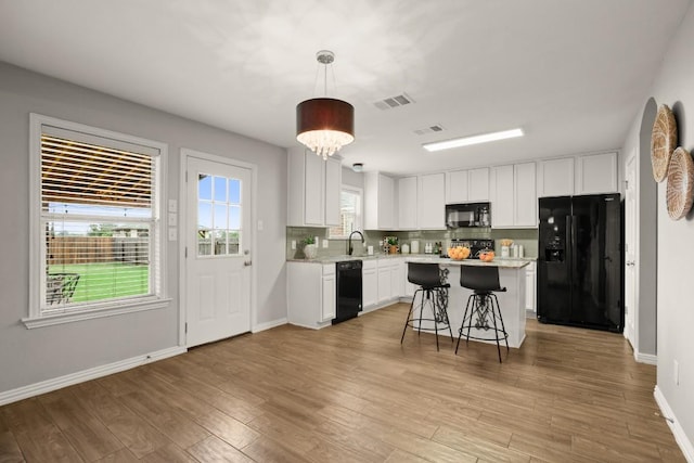 3505 Winding Shore Ln, Pflugerville, TX 78660 - kitchen with black appliances, white cabinets, baseboards, a kitchen breakfast bar, and a center island