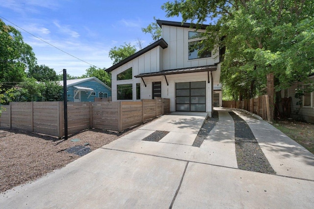 2935 Moss St Unit 1, Austin, TX 78722 - view of front of home featuring concrete driveway, board and batten siding, a garage, and a fenced front yard