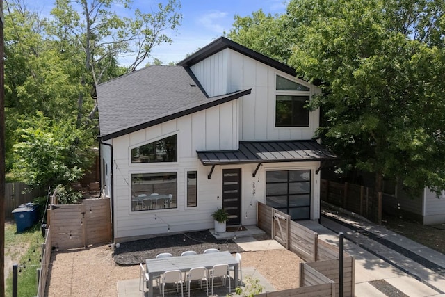 2935 Moss St Unit 1, Austin, TX 78722 - modern farmhouse style home featuring a standing seam roof, outdoor dining area, concrete driveway, an attached garage, and roof with shingles