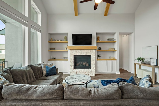17720 Cain Clearing Pass, Austin, TX 78738 - living area with ceiling fan, dark wood finished floors, beamed ceiling, a stone fireplace, and built in features