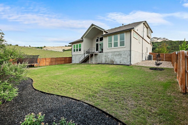 17720 Cain Clearing Pass, Austin, TX 78738 - rear view of house featuring a trampoline, a fenced backyard, stucco siding, and stairs