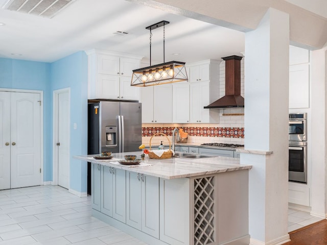 2009 Saint Andrews Dr, Round Rock, TX 78664 - kitchen with stainless steel appliances, wall chimney range hood, tasteful backsplash, white cabinets, and light stone countertops