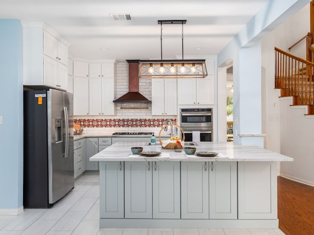 2009 Saint Andrews Dr, Round Rock, TX 78664 - kitchen featuring appliances with stainless steel finishes, wall chimney exhaust hood, tasteful backsplash, light stone counters, and white cabinetry