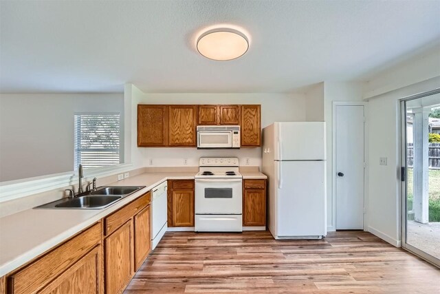 12404 Campana Dr, Del Valle, TX 78617 - kitchen with white appliances, brown cabinets, light countertops, and light wood finished floors
