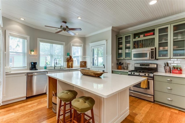 2113 Brooklyn St, Austin, TX 78704 - kitchen with appliances with stainless steel finishes, light countertops, a center island, green cabinetry, and crown molding