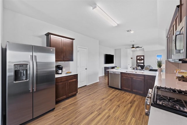 1003 Ascari Ct, Hutto, TX 78634 - kitchen featuring stainless steel appliances, dark brown cabinets, light countertops, light wood-style flooring, and a sink