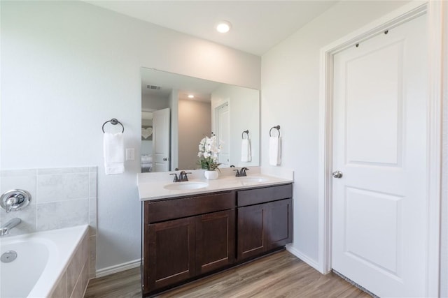 1003 Ascari Ct, Hutto, TX 78634 - full bathroom featuring a garden tub, double vanity, wood finished floors, and baseboards