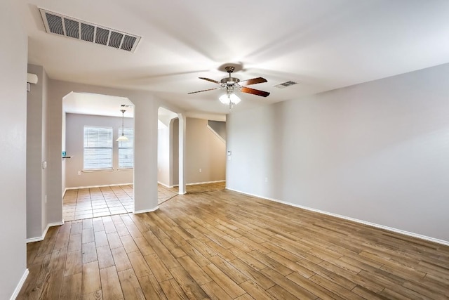 9001 China Rose Dr, Austin, TX 78724 - unfurnished room featuring arched walkways, ceiling fan, wood finished floors, and baseboards