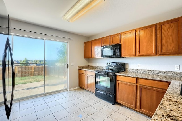 9001 China Rose Dr, Austin, TX 78724 - kitchen featuring black appliances, brown cabinetry, light tile patterned floors, light stone countertops, and baseboards