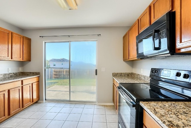 9001 China Rose Dr, Austin, TX 78724 - kitchen featuring black appliances, brown cabinets, baseboards, light tile patterned floors, and light stone countertops