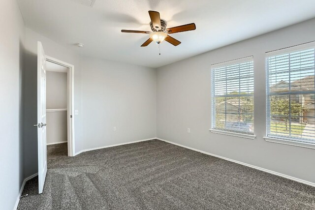 9001 China Rose Dr, Austin, TX 78724 - spare room featuring healthy amount of natural light, dark colored carpet, ceiling fan, and baseboards