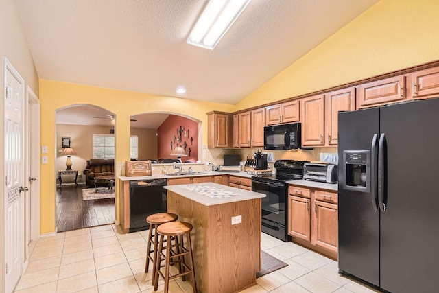 1007 Big Spring Dr, Cedar Park, TX 78613 - kitchen featuring black appliances, arched walkways, a center island, lofted ceiling, and light countertops