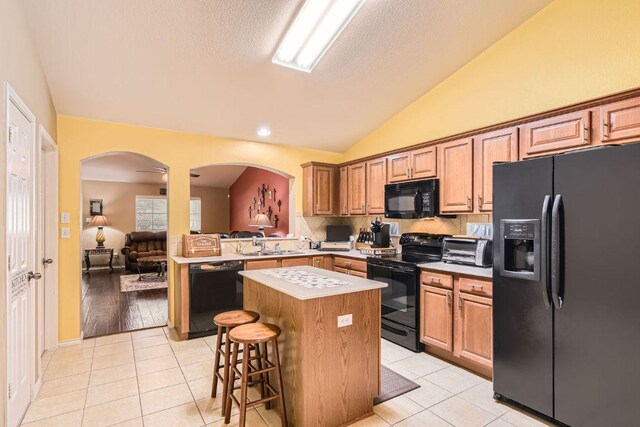 1007 Big Spring Dr, Cedar Park, TX 78613 - kitchen with black appliances, arched walkways, a center island, lofted ceiling, and light countertops