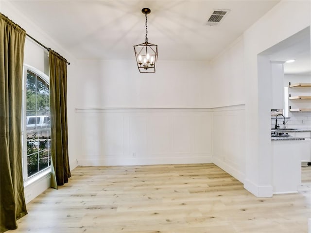 4109 Moss Hollow Dr, Round Rock, TX 78681 - unfurnished dining area with a decorative wall, light wood-style flooring, a chandelier, wainscoting, and a sink