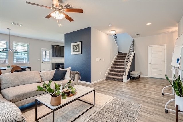 10317 Laurie Ln, Austin, TX 78747 - living area featuring stairs, a ceiling fan, a chandelier, baseboards, and light wood finished floors