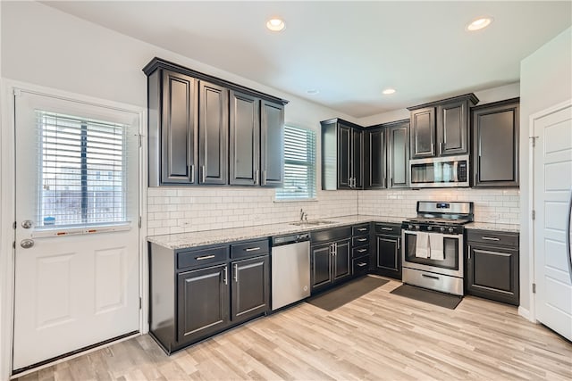 10317 Laurie Ln, Austin, TX 78747 - kitchen with stainless steel appliances, a sink, light stone counters, light wood-style floors, and recessed lighting
