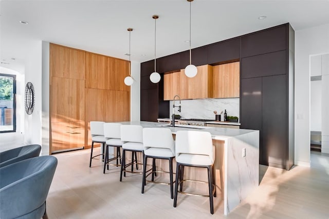 2807 Garwood St, Austin, TX 78702 - kitchen with modern cabinets, a kitchen breakfast bar, tasteful backsplash, a center island with sink, and hanging light fixtures