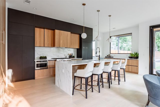 2807 Garwood St, Austin, TX 78702 - kitchen with modern cabinets, light countertops, backsplash, a sink, and a spacious island