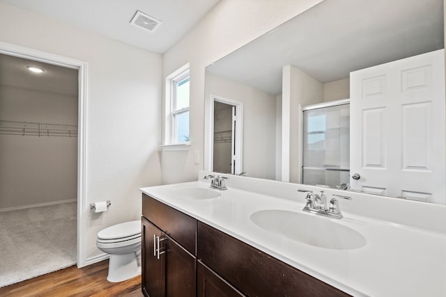 128 Rock Nettle, New Braunfels, TX 78130 - full bathroom featuring toilet, a walk in closet, double vanity, and wood finished floors