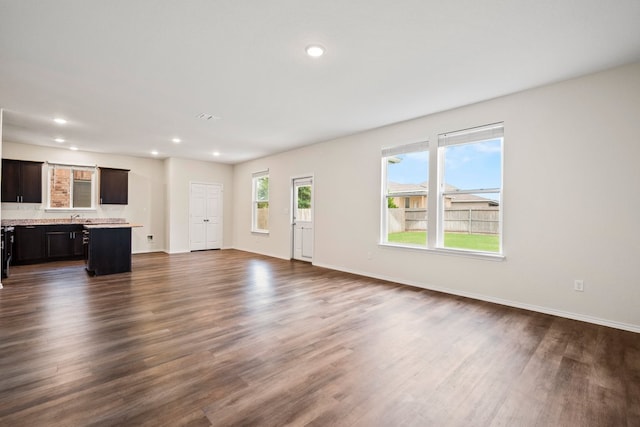 128 Rock Nettle, New Braunfels, TX 78130 - unfurnished living room with dark wood-style flooring, baseboards, recessed lighting, and a sink