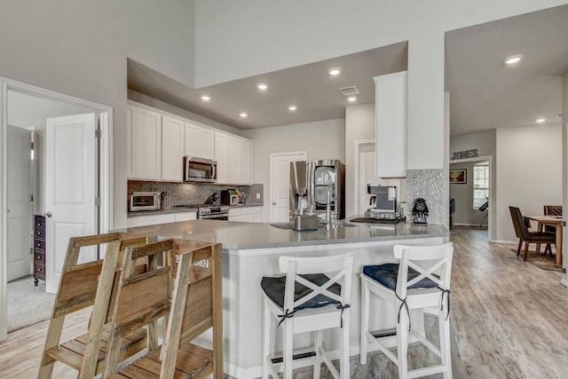 17101 Borromeo Ave, Pflugerville, TX 78660 - kitchen with appliances with stainless steel finishes, backsplash, light wood finished floors, white cabinets, and recessed lighting