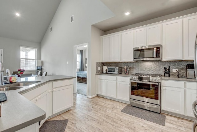 17101 Borromeo Ave, Pflugerville, TX 78660 - kitchen featuring stainless steel appliances, decorative backsplash, white cabinetry, a sink, and high vaulted ceiling