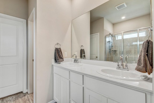 17101 Borromeo Ave, Pflugerville, TX 78660 - full bathroom featuring double vanity, a shower stall, and wood finished floors