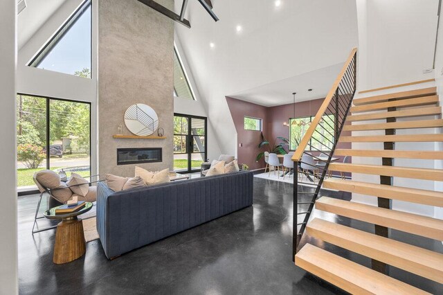 4506 Clawson Rd Unit 1, Austin, TX 78745 - living room featuring a towering ceiling, stairs, a large fireplace, and finished concrete flooring