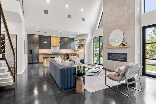 4506 Clawson Rd Unit 1, Austin, TX 78745 - living room with a towering ceiling, stairway, concrete flooring, a glass covered fireplace, and baseboards