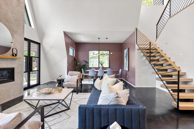 4506 Clawson Rd Unit 1, Austin, TX 78745 - living room with a high ceiling, stairs, finished concrete flooring, baseboards, and a chandelier
