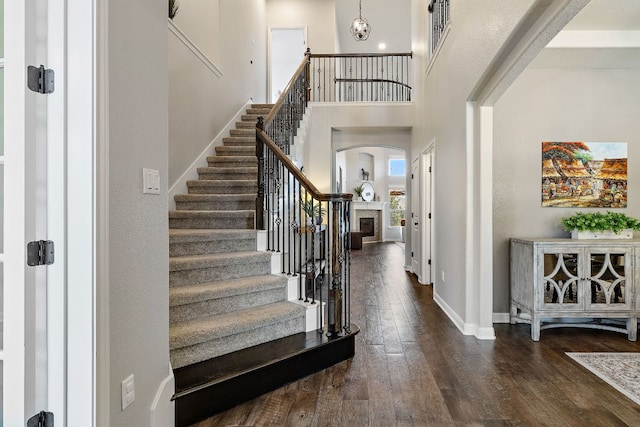 2313 Legend Hill Dr, Leander, TX 78641 - foyer entrance with arched walkways, dark wood-style flooring, stairway, a high ceiling, and a fireplace