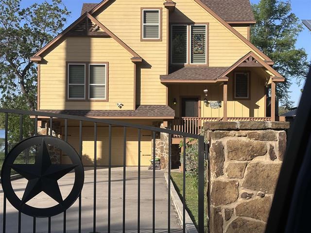 1002 Scenic Loop, Kingsland, TX 78639 - view of front facade featuring roof with shingles, a gate, an attached garage, and board and batten siding