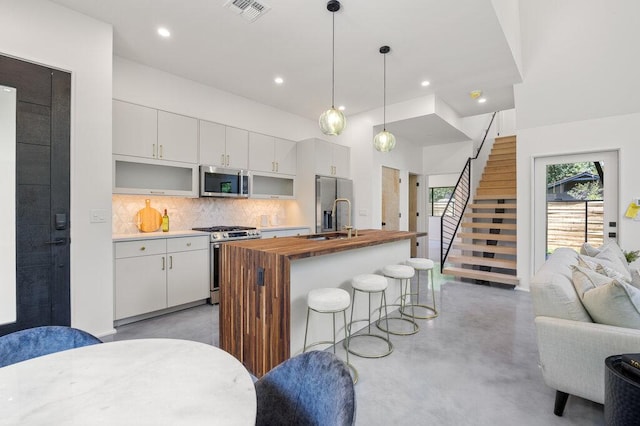 4506 Clawson Rd Unit 2, Austin, TX 78745 - kitchen featuring appliances with stainless steel finishes, open floor plan, concrete flooring, backsplash, and an island with sink