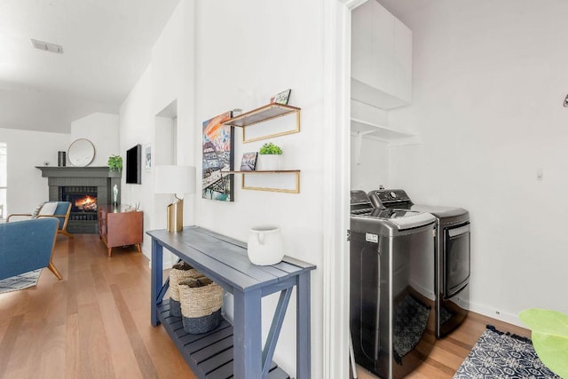 3712 Sawmill Dr, Austin, TX 78749 - laundry area with separate washer and dryer, light wood-type flooring, a brick fireplace, and baseboards