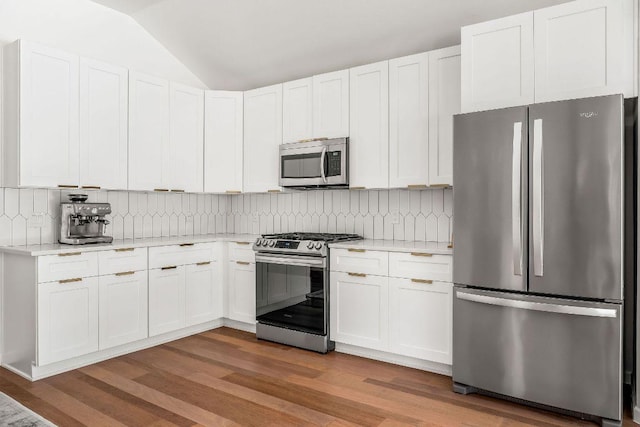 3712 Sawmill Dr, Austin, TX 78749 - kitchen featuring stainless steel appliances, lofted ceiling, light countertops, wood finished floors, and decorative backsplash