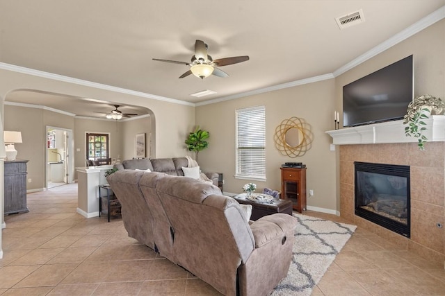 3517 Shellcastle Ln, Round Rock, TX 78681 - living room with arched walkways, light tile patterned floors, ceiling fan, ornamental molding, and a tiled fireplace