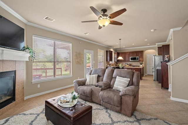 3517 Shellcastle Ln, Round Rock, TX 78681 - living area with light tile patterned flooring, arched walkways, a tiled fireplace, ornamental molding, and a ceiling fan