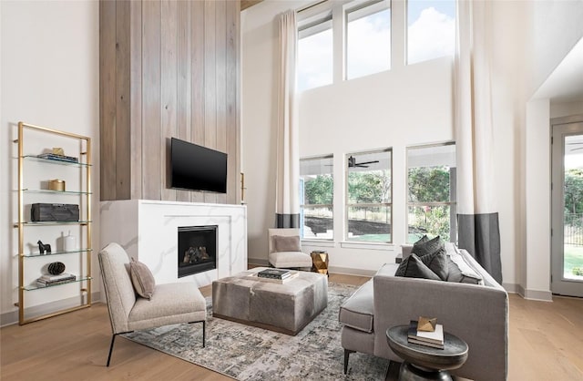 225 Hazy Hills Loop, Dripping Springs, TX 78620 - living area featuring a fireplace, a high ceiling, light wood-style floors, and baseboards
