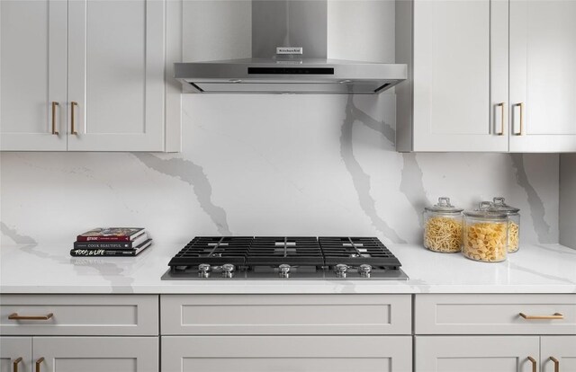225 Hazy Hills Loop, Dripping Springs, TX 78620 - kitchen featuring wall chimney range hood, light countertops, stainless steel gas cooktop, and white cabinets
