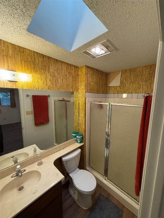 10502 Golden Meadow Dr, Austin, TX 78758 - full bathroom with toilet, a stall shower, vanity, a textured ceiling, and wood walls