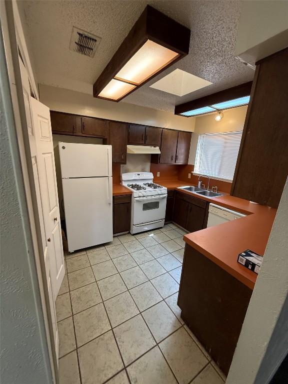 10502 Golden Meadow Dr, Austin, TX 78758 - kitchen with white appliances, a sink, under cabinet range hood, a textured ceiling, and dark brown cabinetry