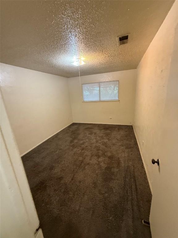 10502 Golden Meadow Dr, Austin, TX 78758 - empty room with a textured ceiling and dark carpet